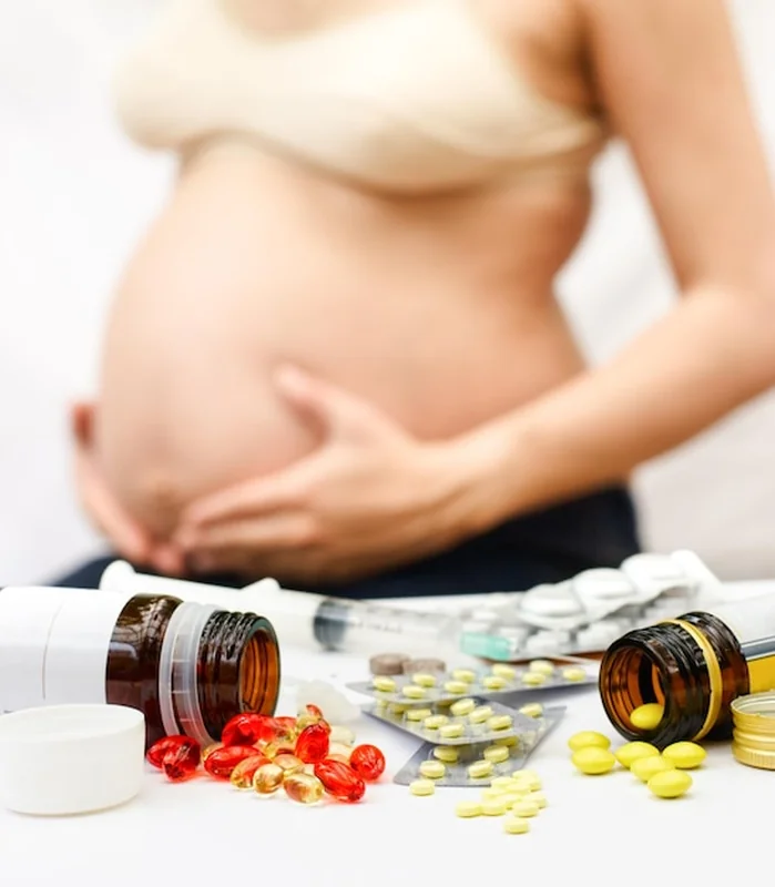 Kobieta w ciąży przed butelekami z tabletkami