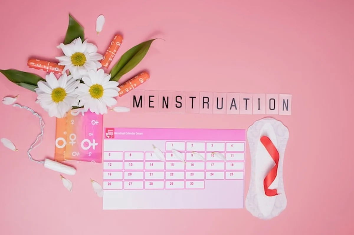 Kalendarz menstruacyjny z akcesoriami higienicznymi i białym kwiatkiem