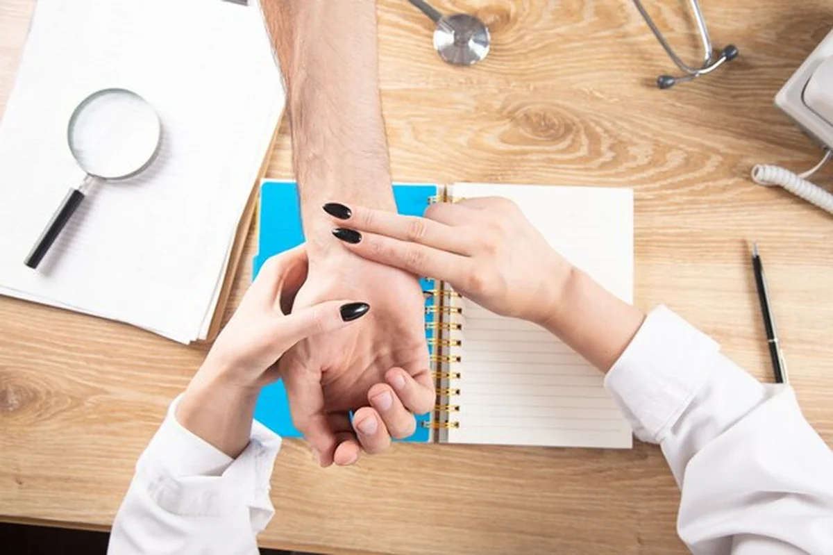 Lekarz sprawdza puls pacjenta przy stole roboczym