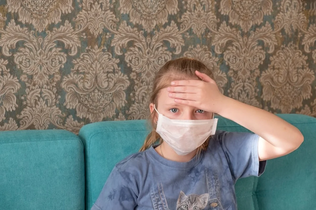 Chora dziewczyna z medyczną maską i bólem głowy